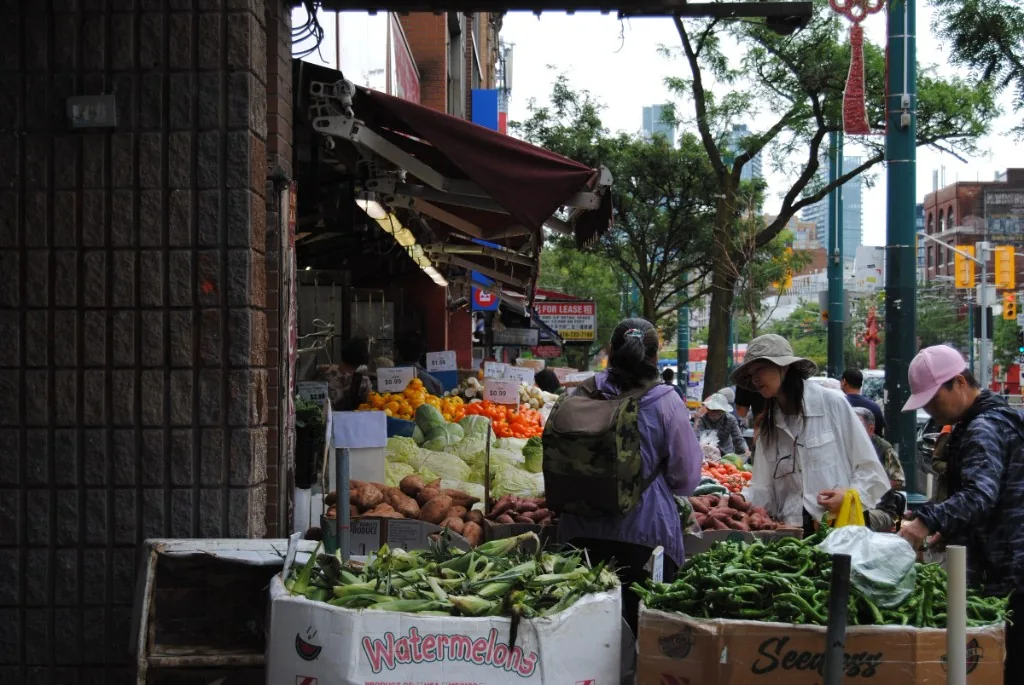 Shoppers browsing crates of produce outside a Chinatown grocer