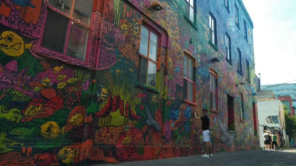 A narrow laneway with both walls covered in large-scale street art